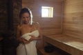 A young woman relaxes and sweats in a hot sauna wrapped in a towel. girl in the