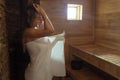 A young woman relaxes and sweats in a hot sauna wrapped in a towel. girl in the