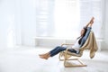 Young woman relaxing in armchair near window. Space for text Royalty Free Stock Photo