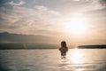 young woman relaxing in beautiful pool at sunset