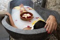 Young woman relaxing in black stone bath with tropical flowers and rose petals. Skin treatment, luxury spa concept Royalty Free Stock Photo