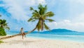 Young woman relaxing at a coconut palm tree on a white tropical beach at La Digue Seychelles Islands