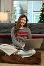 Young woman relaxing on couch and browsing internet on couch. Winter, coziness, leisure and people concept