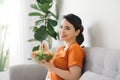 Young woman relaxing on the couch at home and eating a fresh garden salad, healthy lifestyle and nutrition concept Royalty Free Stock Photo