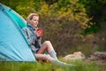 Young woman relaxing with a cup of tea near a tent against green Royalty Free Stock Photo