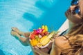 Young woman relaxing and eating fruit plate by the hotel pool. Exotic summer diet. Photo of legs with healthy food by Royalty Free Stock Photo