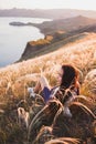 Young woman relaxing in grass field at sunset view mountain and sea coast Royalty Free Stock Photo