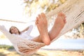 Young woman relaxing in hammock on beach, focus on legs. Summer vacation Royalty Free Stock Photo