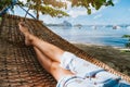 Feet of adult woman relaxing in a hammock on the beach during summer holiday