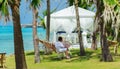 Young woman relaxing on hammock in cozy tropical garden near white gazebo Royalty Free Stock Photo