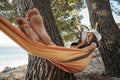 Young woman relaxing in a hammock hanging between trees