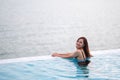 A young woman relaxing in infinity swimming pool with a beautiful sea view Royalty Free Stock Photo