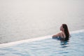 A young woman relaxing in infinity swimming pool looking at a beautiful sea view Royalty Free Stock Photo