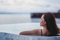 A young woman relaxing in infinity swimming pool looking at a beautiful sea view Royalty Free Stock Photo