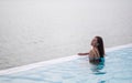 A young woman relaxing in infinity swimming pool looking at a beautiful sea view Royalty Free Stock Photo