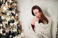 Young woman relaxing with a mug of coffee as she cuddles up in warm blanket on ancient commode. Her eyes closed and
