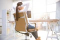 Young woman relaxing in office chair at workplace, back view Royalty Free Stock Photo