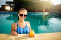 Young woman relaxing in a pool in summer with glass of orange juice. Pretty caucasian blonde girl wearing blue swimsuit Royalty Free Stock Photo