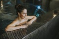 Young woman relaxing on the poolside of indoor swimming pool Royalty Free Stock Photo