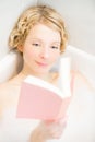 Young woman relaxing and reading a book in the bath Royalty Free Stock Photo