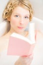 Young woman relaxing and reading a book in the bath Royalty Free Stock Photo