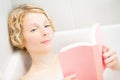 Young woman relaxing and reading a book in the bath Royalty Free Stock Photo