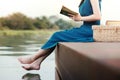 Young Woman Relaxing by Riverside. Sitting on Deck and Reading Book Royalty Free Stock Photo