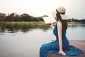 Young Woman Relaxing by Riverside. Sitting on Deck and Reading Book Royalty Free Stock Photo