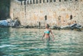 Young woman relaxing in sea at beach near fortress wall