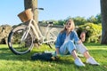 Young woman relaxing sitting on grass in park using smartphone