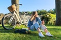 Young woman relaxing sitting on grass in park using smartphone