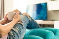 Young woman relaxing on the sofa at home, watching tv and enjoying coffee Royalty Free Stock Photo