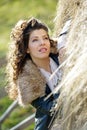 Young woman relaxing under a hay stack in autumn