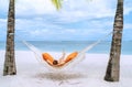 Young woman relaxing in wicker hammock on the sandy white beach on Mauritius coast and enjoying wide ocean view waves. Exotic Royalty Free Stock Photo