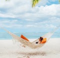 Young woman relaxing in wicker hammock on the sandy white beach on Mauritius coast and enjoying wide ocean view waves. Exotic Royalty Free Stock Photo