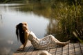 Young woman relaxing on the wooden pier at the calm lake Royalty Free Stock Photo