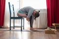 Young woman in relaxing yoga pose called balasana or child pose sitting on chair