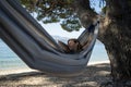 Young woman relaying and enjoying in a hammock by the beach