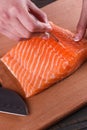 Young woman removes bones from a salmon fillet