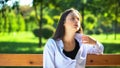 Young woman resting on bench in park suffering from heat and stuffiness, pms Royalty Free Stock Photo