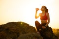 Woman Resting and Drinking Water after Running Outdoor. Workout at Hot Summer Sunset. Sport and Healthy Active Lifesyle.