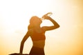 Woman Resting and Drinking Water after Running Outdoor. Workout at Hot Summer Sunset. Sport and Healthy Active Lifesyle.