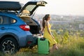 Young woman resting on a green suitcase near her car in summer nature. Travel and vacations concept Royalty Free Stock Photo