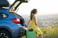 Young woman resting on a green suitcase near her car in summer nature. Travel and vacations concept Royalty Free Stock Photo