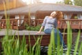 Young woman resting and having fun in the park sitting on a pier over the lake. Royalty Free Stock Photo