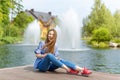 Young woman resting and having fun in the park sitting on a pier over the lake. Royalty Free Stock Photo