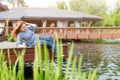 Young woman resting and having fun in the park sitting on a pier over the lake. Royalty Free Stock Photo