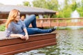 Young woman resting and having fun in the park sitting on a pier over the lake. Royalty Free Stock Photo