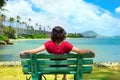 Young woman resting on park bench along Hawaiian ocean Royalty Free Stock Photo