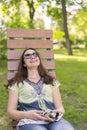 Young woman resting in the park on the bench. Beautiful female relaxing on a park bench and using a smartphone. toned Royalty Free Stock Photo